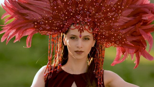 A beautiful young woman in a carnival costume and a crown of feathers. Super slow motion