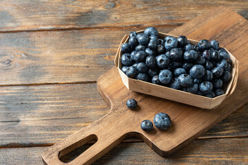 Blueberries in a wooden box on a brown wooden table. Fresh blueberries in a box. Space for text