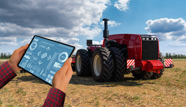 A farmer with digital tablet controls an autonomous tractor on a smart farm