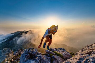 Sky runner man uphill on rocks at sunset - 376380392