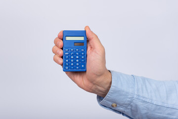 Male hand holding calculator on white background. Financial activity. Accounting