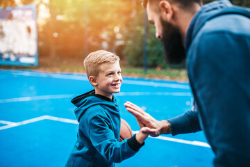 Father and his son enjoying together on basketball court.