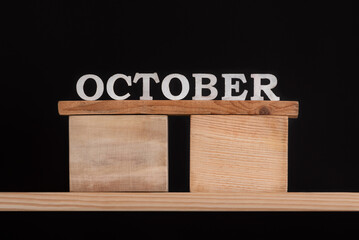 Word October by wooden letters on black background. Front view. Autumn calendar. Fall month