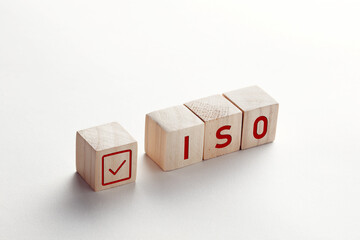 The abbreviation ISO on wooden cubes with check mark on white background. ISO quality control certification approval concept.