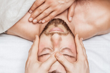 Fototapeta na wymiar Man receiving relaxing head massage by massage therapist hands, top view.