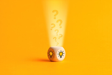 Question mark icons are filling into a wooden cube with light bulb icons. Idea generation, decision...