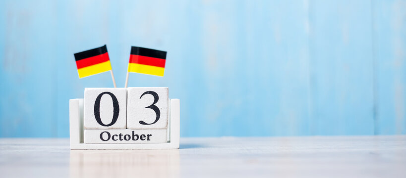 Wooden calendar of October 3rd with miniature Germany flags. German Unity Day and happy celebration concepts