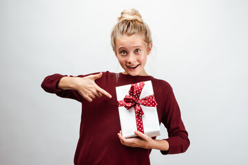 Beautiful blonde girl 10-12 years old dressed in casual sweater, holding gift box