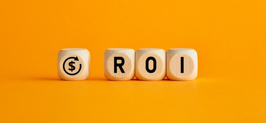 The word ROI return on investment written on wooden cubes with on yellow background. Profit or loss analysis in business and finance concept.