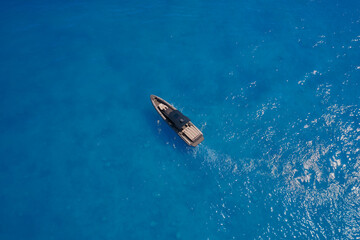 Aerial view of a yacht on blue water. Lonely boat mooring on the water. luxury motor boat. Drone view of a boat. Top view of a white boat in the blue sea.