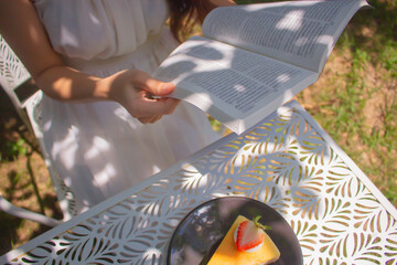 Women hands holding the book to reading in the garden at cafe. Relaxation and reading concept. Weekend activity concept.