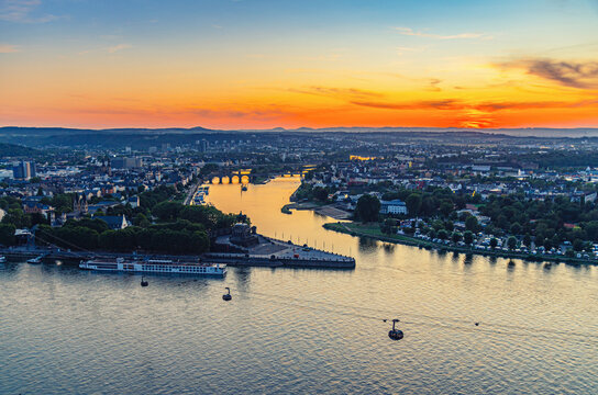 Aerial Panoramic View Of Koblenz Historical City Centre And Joining Rhine And Moselle Rivers, Evening Twilight View Of Amazing Colorful Orange Sunset On Horizon, Rhineland-Palatinate State