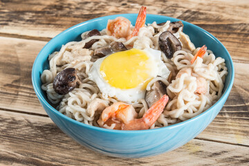 Chinese soup with udon noodles, pork, boiled eggs, mushrooms and prawns close-up in a bowl on the...