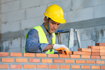 Brick mason,Construction worker installing red brick with trowel putty knife for new house building at construction site.