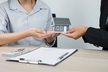 Fototapeta premium Real estate agent broker hand over the home to the new owner after completing the signing according to agreement renting a house and buy house insurance Home rental and insurance concept