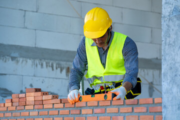 Professional worker building brick walls with cement.