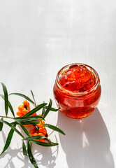Homemade jam made from the orange berries of sea buckthorn on a white background. Copy space.