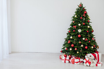 The interior of the white room is a green Christmas tree with red gifts for the new year holiday decor