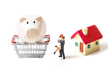 miniature couple with tiny home and piggy bank isolated on white background.