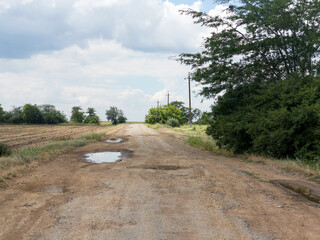 Damaged asphalt pavement road with potholes caused by freeze and thaw cycle during winter.
