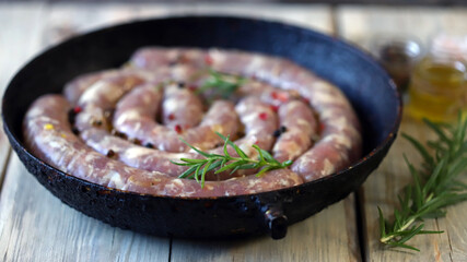 Selective focus. Raw homemade sausages with spices in a pan. Rustic style.