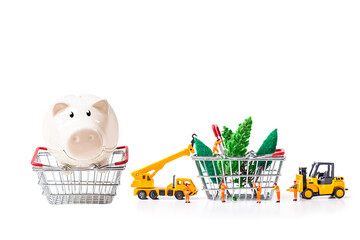 Piggy bank with miniature worker passenger Christmas box and pine cone by truck and forklift to shopping basket isolated on white background