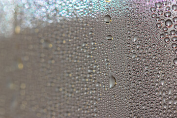 Many colorful little drops on the glass surface close-up in the autumn morning
