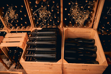 Glass bottles of wine stored in wooden crates and wine racks