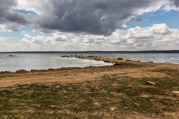 A herd of goats is saved from the heat on the spit of the lake shore. Farm animals, goats on the burnt bank of the lake before the rain. A farm of a herd of goats on the river bank