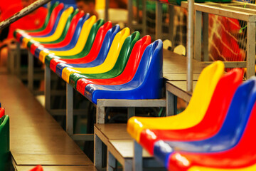 Fototapeta na wymiar Multicolored Empty plastic chairs in the stands of the stadium. Many empty seats for spectators in the stands. Empty plastic chairs for football fans in the gym. Bright colorful seats for stadium fans
