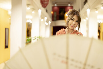 Asian beautiful woman in traditional Japanese kimono with an umbrella  and smiling at camera,...