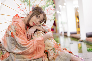 Young woman in traditional Japanese kimono with an umbrella  and looking at camera, Japanese concept of kimono and yukata.