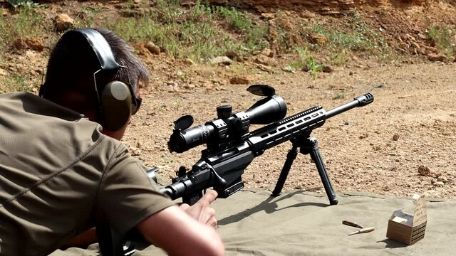 Shooter at the shooting range shoots with a sniper rifle