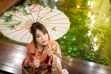 Traditional Japanese kimono girl with umbrella and looking at camera, Japanese tradition concept,...