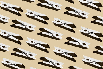Naklejka premium Pattern of wooden white clothespins on a pastel beige background.