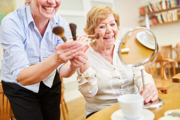 Cheerful senior woman applying makeup in front of the mirror