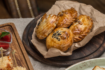 Fresh baked homemade buns with sesame samsa on wooden plate on the table