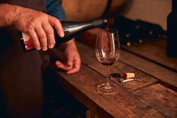 Fototapeta na wymiar Male sommelier pouring red wine into glass