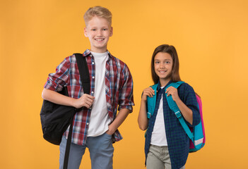 Schoolchildren posing with schoolbags at studio background