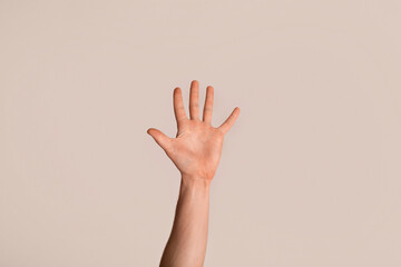 Young guy showing his hand with open palm, gesturing high five on light background, closeup