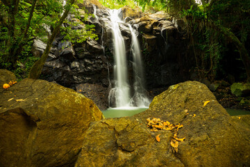 Waterfall landscape. Beautiful hidden waterfall in tropical rainforest. Foreground with big stones. Slow shutter speed, motion photography. Sing Sing Angin waterfall, Bali, Indonesia