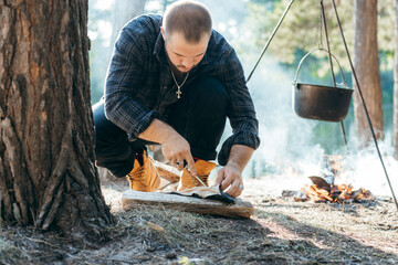 A man with a knife cuts fish in forest