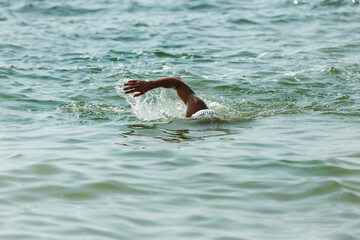 Swimmer swims in sea. Athlete triathlete swimmer drains from water. A professional athlete in...