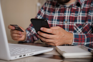 Handsome man using credit card to pay online with smartphone