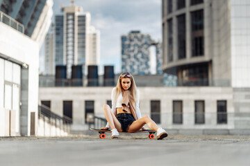 Young woman rides a longboard around the city.