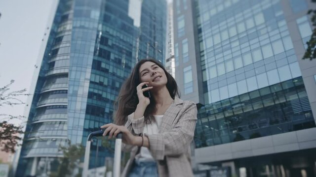 Portrait of beautiful businesslady checking phone. Woman looking at gadget, chatting during business trip. Background of skyscrapers and traffic on street. Concept of job, lifestyle, technology.