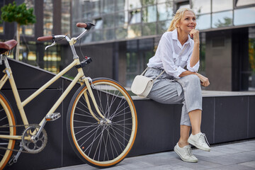 Fototapeta na wymiar Pretty woman in white business clothes with bike in the city
