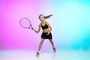 Running high. Little tennis girl in black sportwear isolated on gradient background in neon light. Little caucasian model, sport kid training in motion and action. Sport, movement, childhood concept.