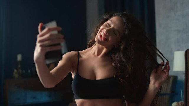 Hot woman taking selfie mobile phone in bedroom. Girl having fun with phone bed
