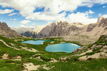blue mountain lake, dolomites, italian alps. green meadows, feeling of freshness, blue sky with clouds, and rocky peaks. nature without pollution, no human presence.